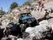 1988 Ford Bronco - A teal off-road truck is shown navigating a rocky terrain with people watching from above.