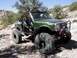 1988 Ford Bronco - This heavily modified off-road vehicle navigates a rocky, desert-like terrain under a clear blue sky.