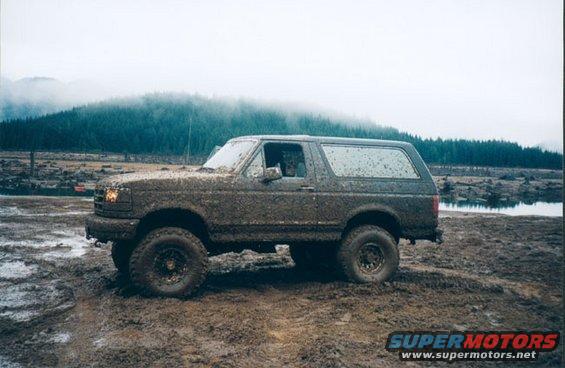 Mud-covered 1993 Ford Bronco side view in a muddy field