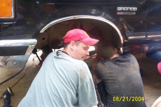 Black Ford Bronco side view, men working on suspension