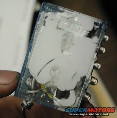 Clear plastic electronic part with white sealant and metal connectors