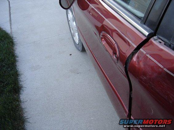 Red 1998 Mercury Sable sedan door, side view, showing damage to the door seam and scratches