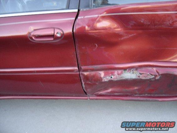Red car door with heavy damage and rust near the bottom