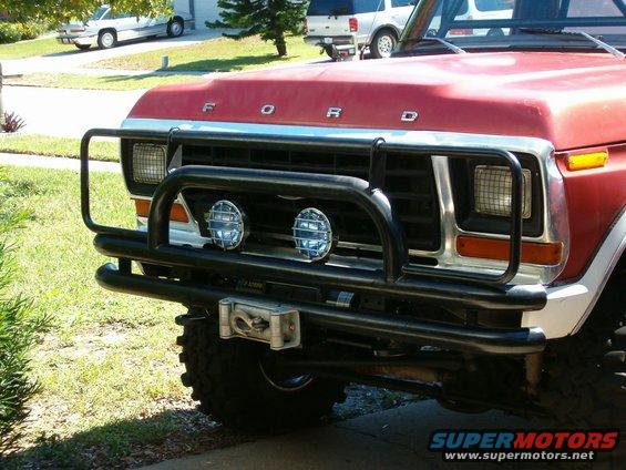 Red 1979 Ford Bronco front end with black bull bar, winch, and two auxiliary lights