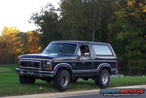 Black 1986 Ford Bronco parked on grassy shoulder