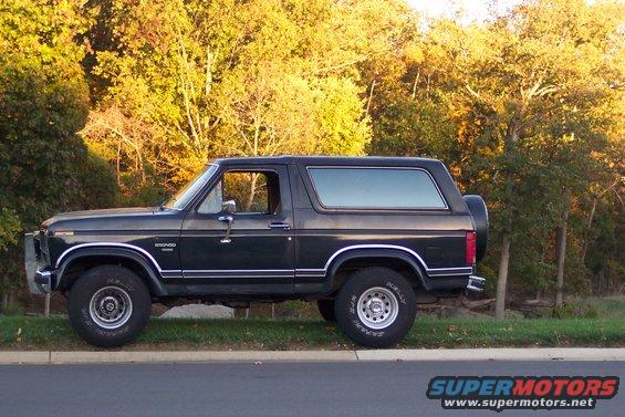 1986 Ford Bronco parked on the side of the road with trees in the background