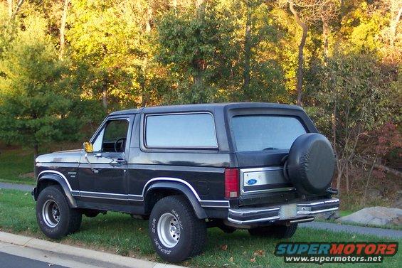 1986 Ford Bronco parked on grass, rear quarter view. Spare tire mounted on back