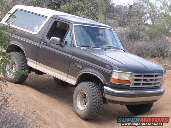 1995 Ford Bronco with lifted suspension driving on a dirt trail