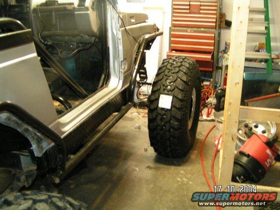 Off-road tire next to open vehicle door, showing interior roll cage