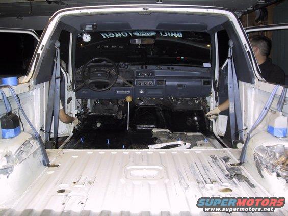 1993 Ford Bronco interior stripped down, showing dashboard, steering wheel, and empty floor. White body panels are visible