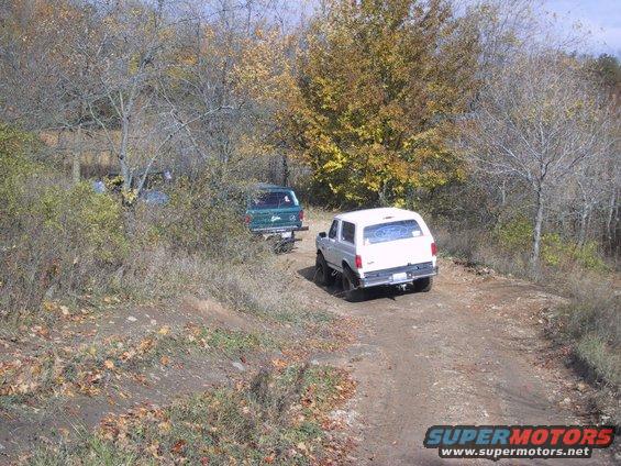 1993 Ford Bronco and a green SUV on a dirt road during fall