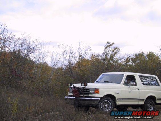 1993 Ford Bronco parked off-road with auxiliary lights and a red gas can on the front bumper