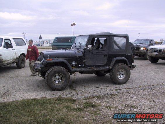 Black Jeep Wrangler parked next to a white SUV, with other vehicles behind