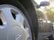 1995 Nissan 240SX - Close-up of a silver Nissan wheel and the side fender of a dark car, with sunlight reflecting off the paint.