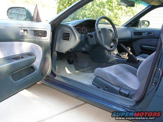 Interior view of a car with grey seats and dashboard. Open driver's door