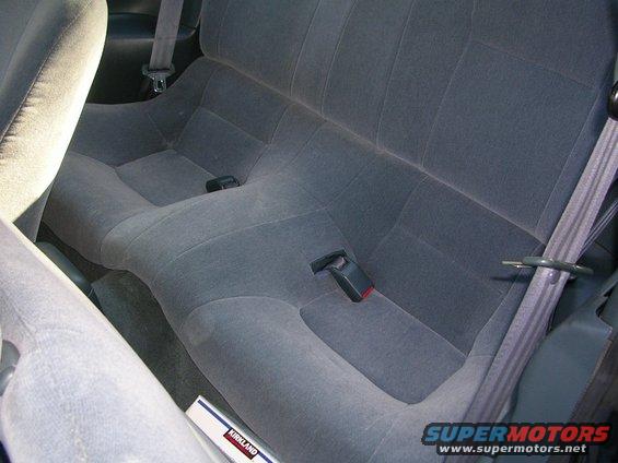 Gray fabric rear car seats with seat belts. A Kirkland box is visible on the floor