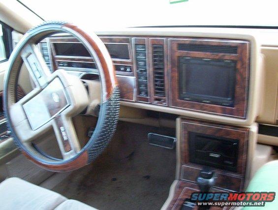 Car interior with wood trim, digital screen, and steering wheel