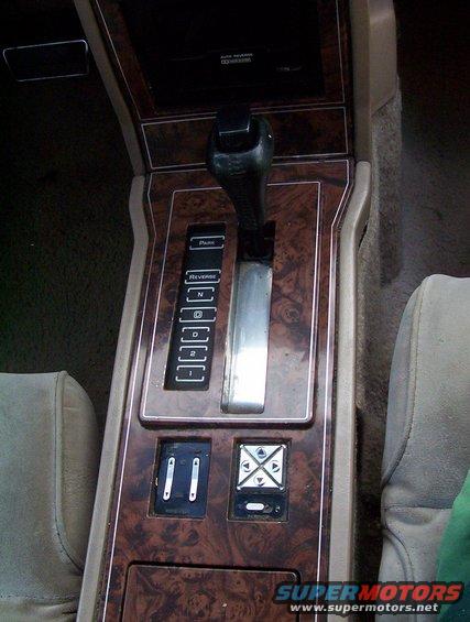 Car interior center console showing automatic shifter, wood grain trim, and control buttons