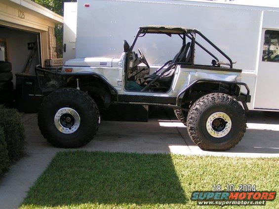 Silver off-road vehicle with roll cage and large tires, parked in driveway