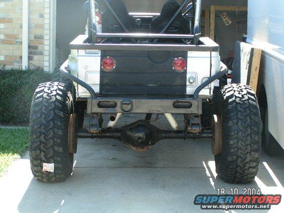 Modified Jeep CJ rear axle with large off-road tires, custom bumper, and roll cage visible
