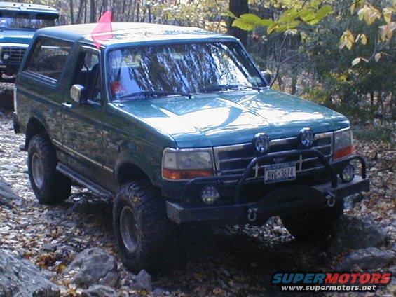 Green SUV with off-road tires and brush guard on rocky terrain