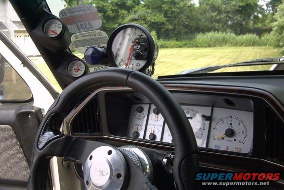 Interior view of a truck dashboard with aftermarket gauges and a steering wheel