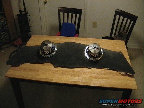 Two car subwoofers on a dark felt pad on a table