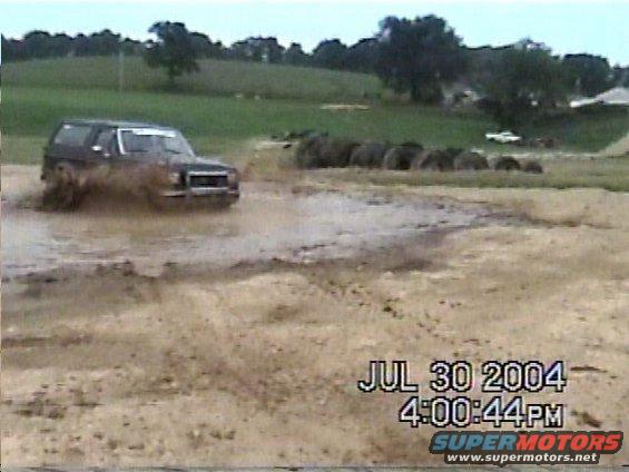 Dark SUV splashing through mud, front view. Date stamp shows July 30, 2004