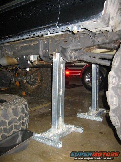 Underbody of black SUV on jack stands with large tires visible