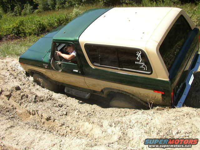 Driver points while 1978 Ford Bronco is stuck in mud