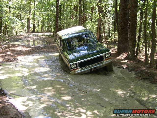 Green 1978 Ford Bronco navigating a muddy trail