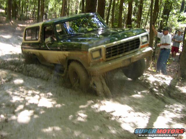 1978 Ford Bronco navigating a muddy trail in a forest