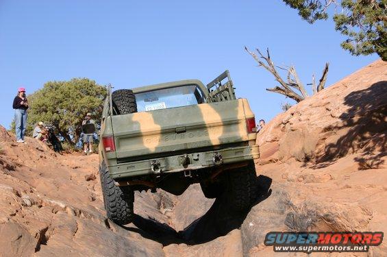 Camouflaged pickup truck climbing a rocky incline
