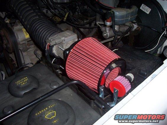 Aftermarket red cone air filter installed on a vehicle's intake system. Includes a smaller pink filter