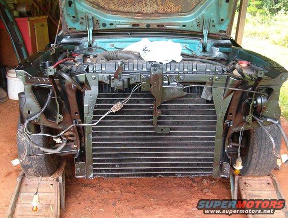 Front end of a car in restoration, showing the radiator and engine bay components