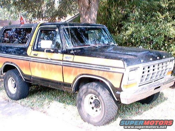 Ford Bronco with black top and orange/yellow side stripe. Front grille visible