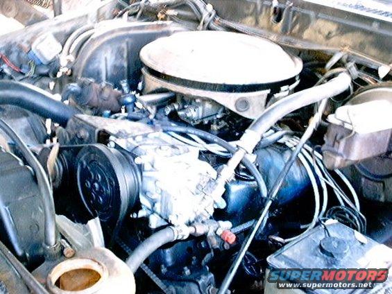 engine bay with air cleaner, compressor, and hoses visible