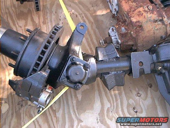 Front axle assembly with disc brake rotor and caliper, mounted on plywood