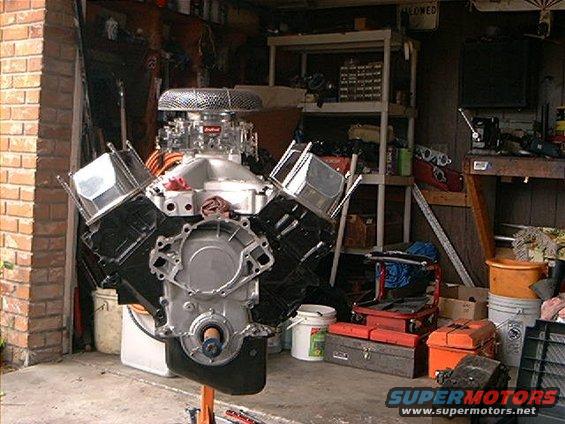 Engine on an orange stand in a garage, with a chrome air filter and aluminum intake manifold