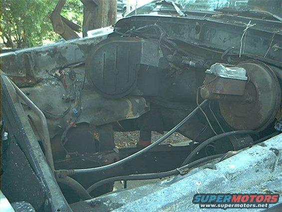 Engine bay with master cylinder and brake booster visible, showing significant damage and rust