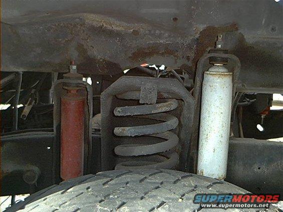 Close-up of front suspension with red and white shocks and coil spring