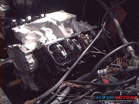 Engine with aluminum intake manifold and exposed valve train, wires and hoses visible