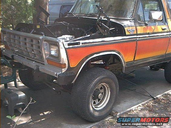 Front end of a 1978 Ford Bronco with hood open, showing orange and yellow side stripes