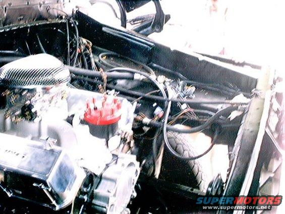 Engine bay with V8 engine, carburetor, and distributor. Wires and hoses are visible
