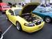1978 Ford Mustang II - A bright yellow Ford Mustang from the early 2000s is displayed with its hood open at a car show.