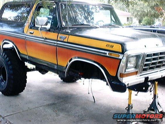 1979 Ford Bronco with orange and yellow stripes, lifted on jack stands