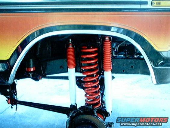 Close-up of red coil springs and white shock absorbers on a vehicle's suspension system