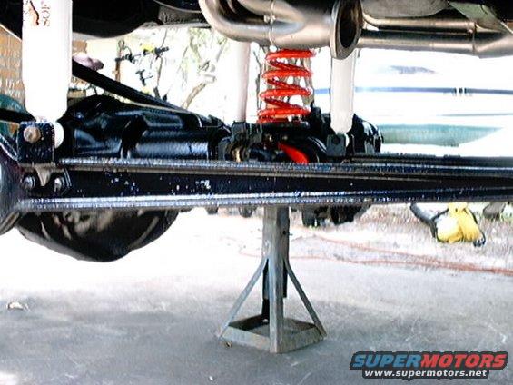 Undercarriage view with red coil springs and jack stand. Supermotors.net logo visible