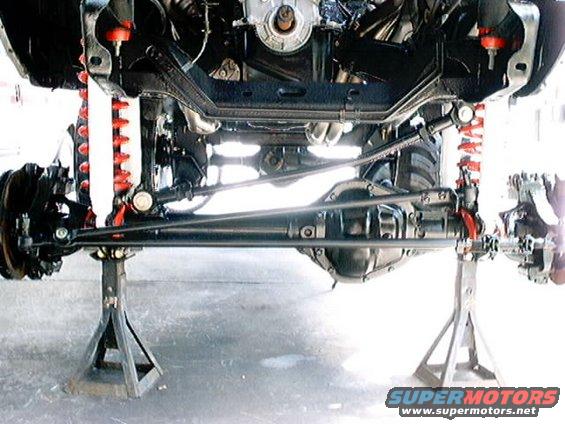 Underside of a vehicle on jack stands, showing suspension and drivetrain components