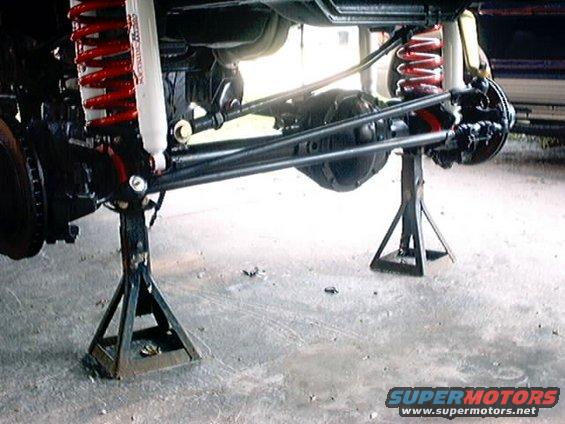 Front axle and suspension on jack stands, red coil springs, white shocks